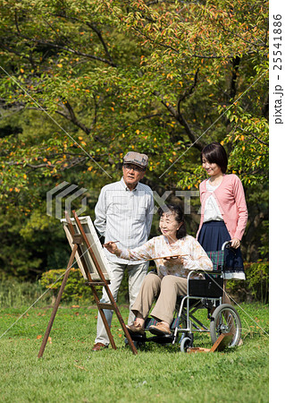 趣味の絵画を楽しむ車いすに乗った初老の妻と夫と孫娘 25541886