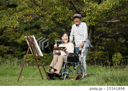 趣味の絵画を楽しむ車いすに乗った初老の妻と介助する夫 25541898