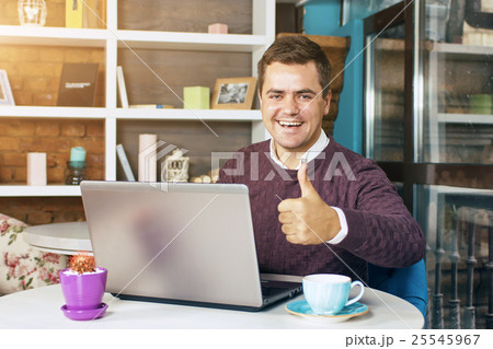 Man in a cafe with laptop smiling 25545967