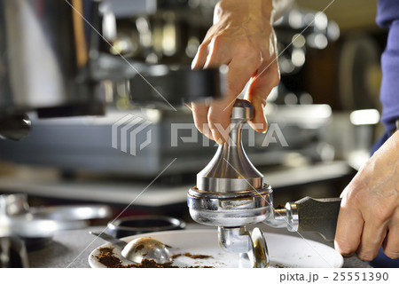 Barista using a tamper to press ground coffee Barista using a tamper to press ground coffee 25551390