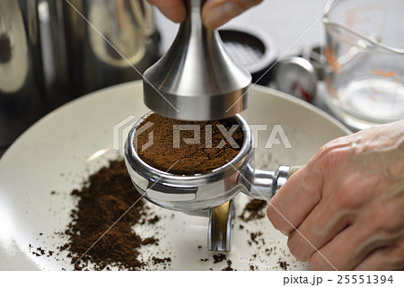 Barista using a tamper to press ground coffee  Barista using a tamper to press ground coffee  25551394