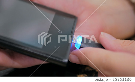 Woman's hand plugging black lightning charging cable into smartphone 25553130