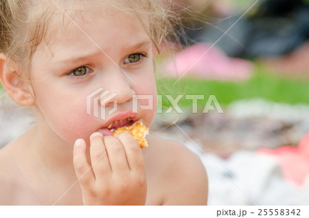 Girl eating cookies and drinking juice from a plastic disposable cup Girl eating cookies and drinking juice from a plastic disposable cup 25558342