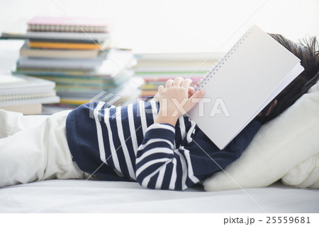 child sleeping on white bed with book 25559681