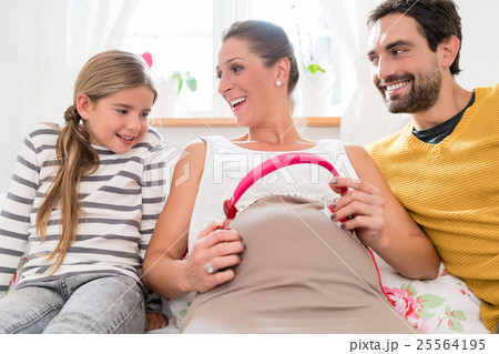 Pregnant mum using headphone on baby belly 25564195