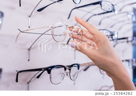 Woman taking glasses out of shelf in store Woman taking glasses out of shelf in store 25564262