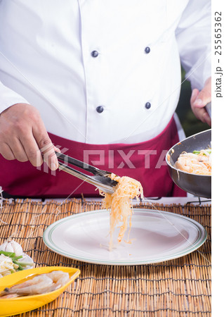 Chef fork over noodles by tongs 25565362