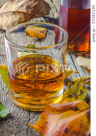 glass of whiskey with autumn leaves on the wooden  25567295