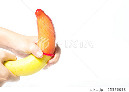 Female hand puts on a condom onto a banana Female hand puts on a condom onto a banana 25576058