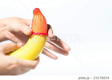Female hand puts on a condom onto a banana 25576059