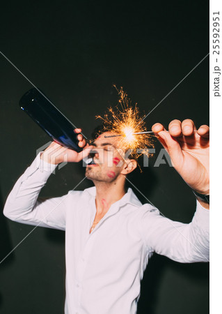 Handsome man with sparkler drinking champagne 25592951