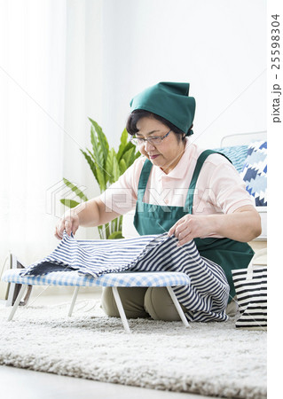 アイロンをかけるシニアハウスキーパー 25598304