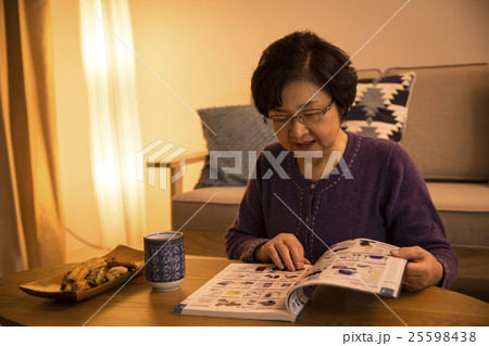 夜に雑誌を読むシニア女性 25598438