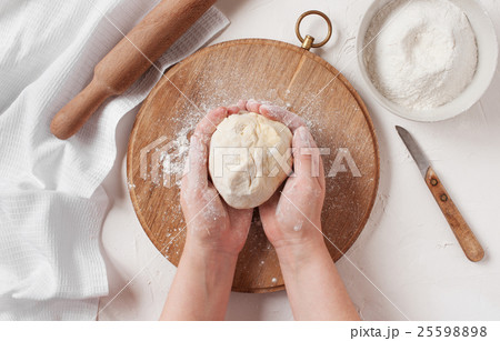 Women's hands holding the ball of dough 25598898