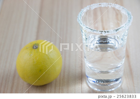 Vodka shot and salt sea, lemon on wooden table Vodka shot and salt sea, lemon on wooden table 25623833