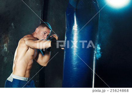 Male boxer boxing in punching bag with dramatic Male boxer boxing in punching bag with dramatic 25624868