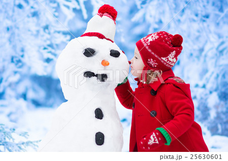 Little girl building snow man in winter Little girl building snow man in winter 25630601