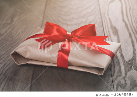 rustic present box with red ribbon on wood table rustic present box with red ribbon on wood table 25640497