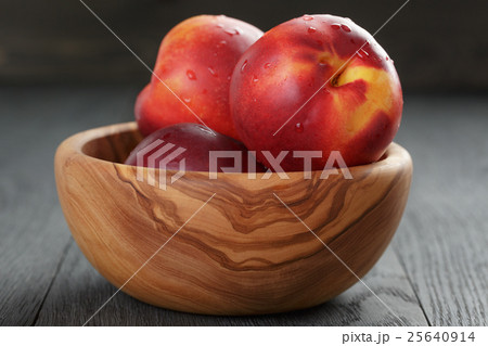 nectarines in olive wood bowl on oak table 25640914