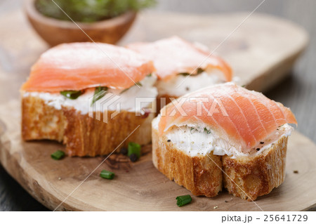 baguette slices with soft cheese and salmon on wood table 25641729