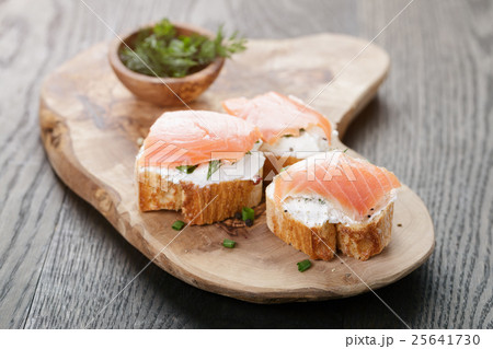 baguette slices with soft cheese and salmon on wood table 25641730