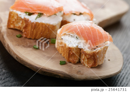 baguette slices with soft cheese and salmon on wood table 25641731