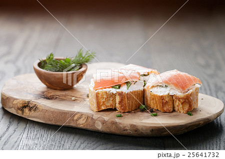 baguette slices with soft cheese and salmon on wood table 25641732