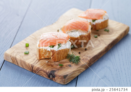 baguette slices with soft cheese and salmon on wood table 25641734