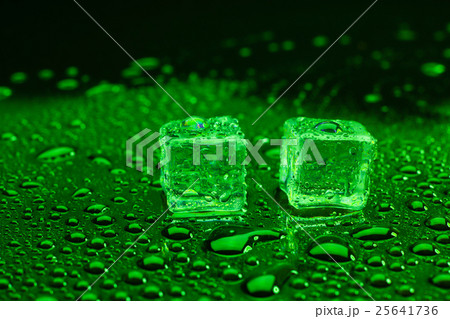 ice cubes on lighting green background. 25641736