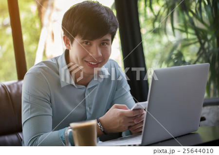 Young Asian man using laptop and smart phone 25644010