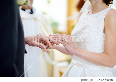 Bride putting a ring on groom's finger 25644846