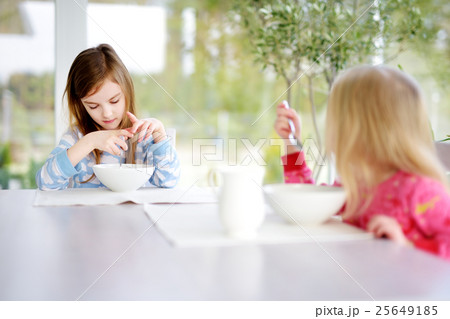 Two cute little sisters having oatmeal for breakfast 25649185