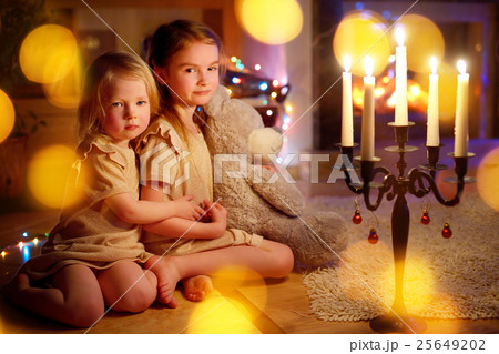 Happy girls sitting by a fireplace on Christmas eve 25649202