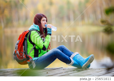 Young brunette drinking water from bottle at pond 25651811