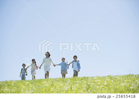 草原で手をつなぐ小学生と先生 草原で手をつなぐ小学生と先生 25655418