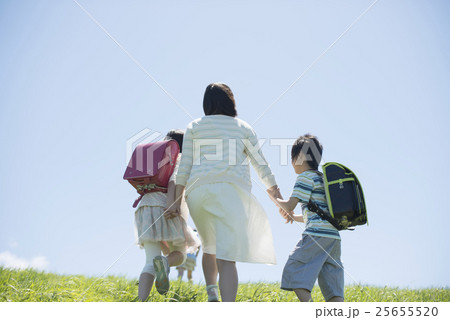 草原で手をつなぐ小学生と先生の後姿 草原で手をつなぐ小学生と先生の後姿 25655520