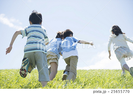草原を走る小学生の後姿の写真素材