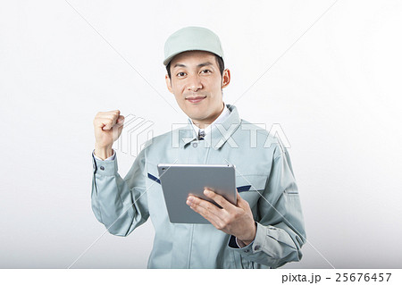 タブレットを持ってガッツポーズをする作業服の男性 タブレットを持ってガッツポーズをする作業服の男性 25676457