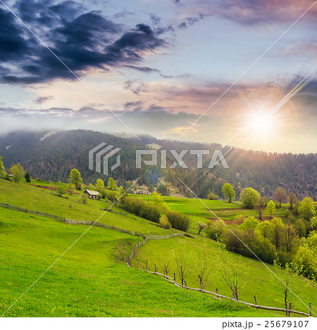 fence on hillside meadow in mountain at sunset 25679107