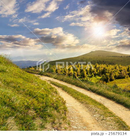 road on a hillside near mountain peak at sunset 25679134