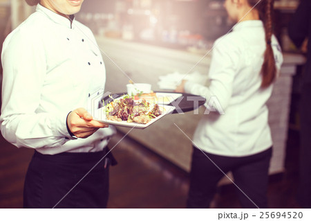 Waiters carrying plates with 25694520