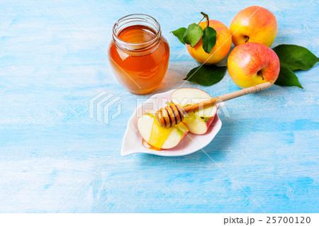 Apple slices with honey on blue wooden background Apple slices with honey on blue wooden background 25700120