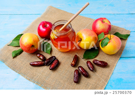 Glass honey jar, dates and apples on burlap napkin Glass honey jar, dates and apples on burlap napkin 25700370