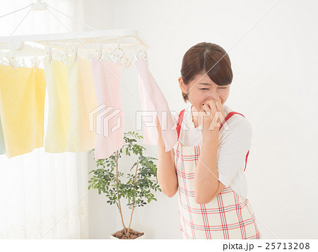 室内干しした洗濯物が臭くて鼻をつまむ女性 25713208