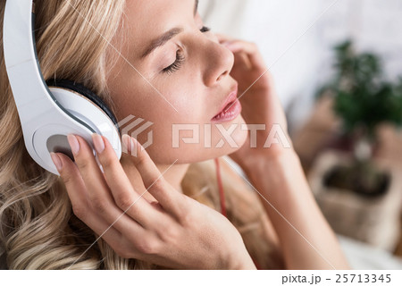 Close up of blond woman listening to music 25713345