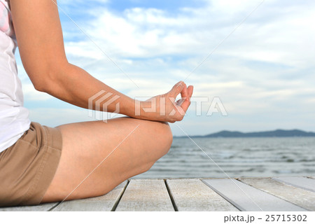 Woman practicing yoga meditation on the beach 25715302
