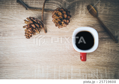 Cup of coffee and brown pine cone on wooden table. 25719608