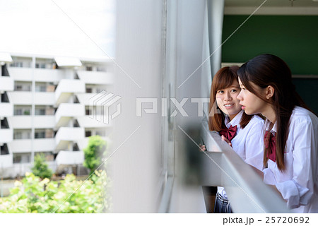 教室の窓から外を見る高校生二人 学生の写真素材