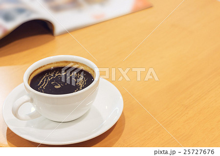 White cup of coffee with magazine on wood table. White cup of coffee with magazine on wood table. 25727676