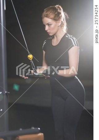 Woman at the sport gym doing arms exercises on a Woman at the sport gym doing arms exercises on a 25734254
